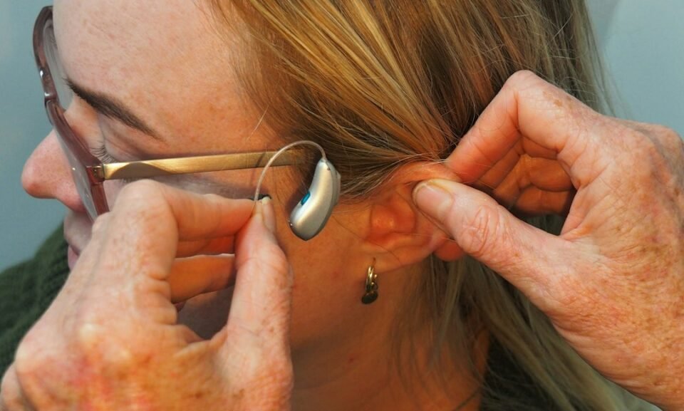 Audiologist fitting a receiver-in-canal hearing aid